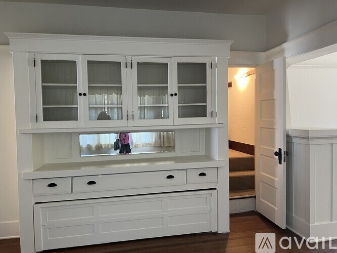 A white cabinet with glass doors and drawers is in a room.
