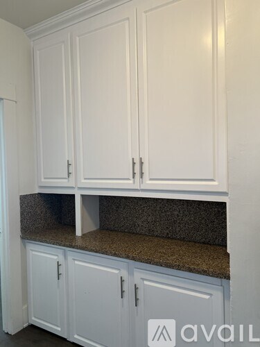 A kitchen with white cabinets and a granite countertop.