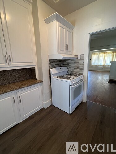 A kitchen with white cabinets and a white stove top oven.