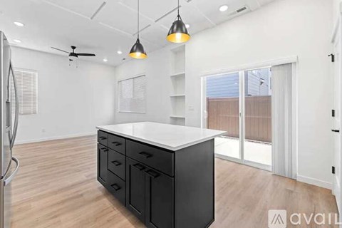 A kitchen with a black island and wooden floors.