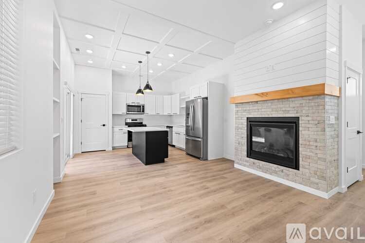 A modern kitchen with a brick fireplace and wooden floors.