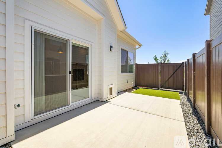A white house with a glass door and a green mat on the concrete walkway.