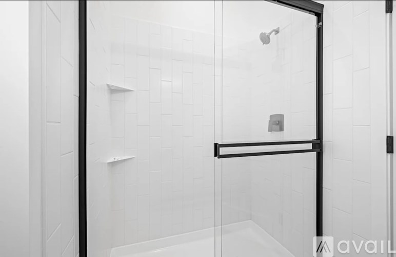 A bathroom with a glass shower door and a black handle.