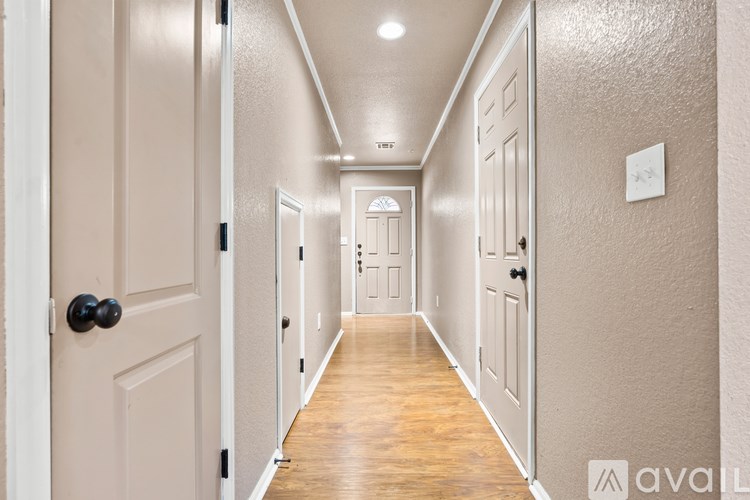 A long hallway with doors on both sides and a light on the wall.