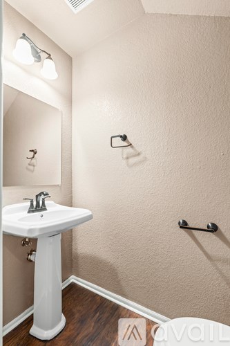 A white pedestal sink in a small bathroom with a mirror and a towel bar.