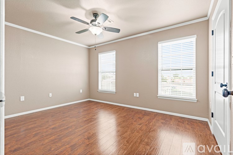 A room with a ceiling fan and wooden flooring.