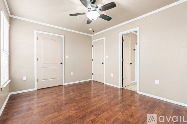 A room with a ceiling fan and wooden flooring.