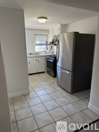 A kitchen with a black fridge and a white wall.