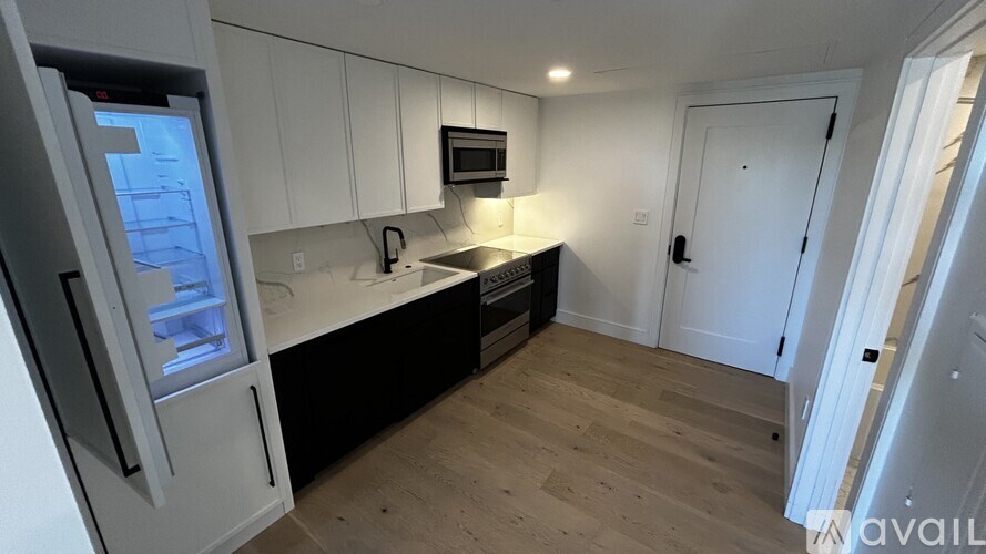 A kitchen with white cabinets and a black countertop.