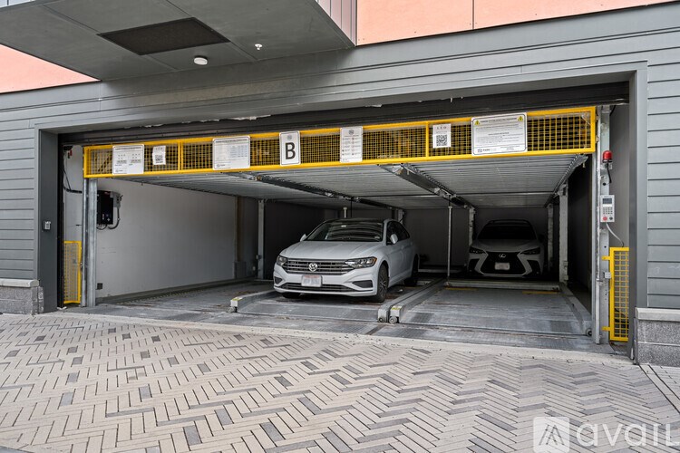 A white car is parked in a garage with a yellow railing.