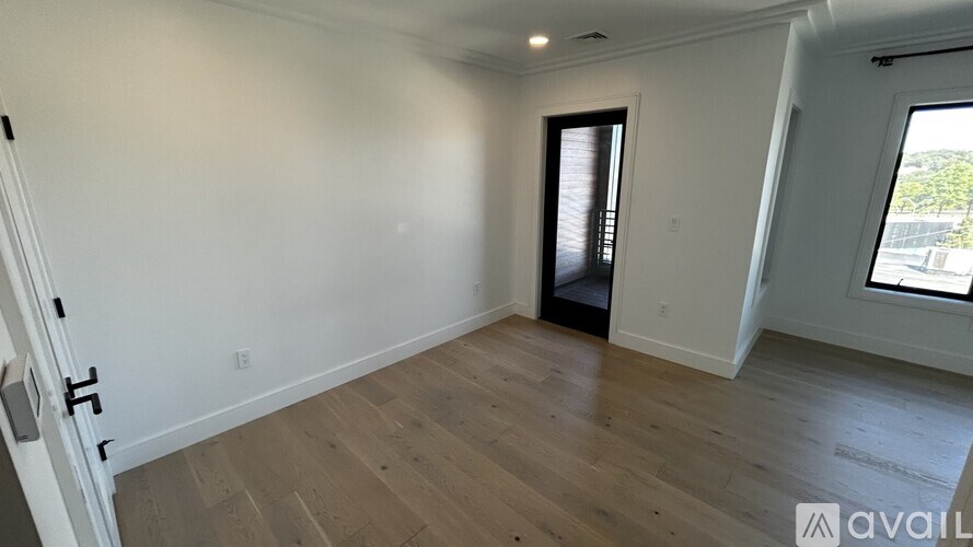 A room with wooden flooring and a window with blinds.