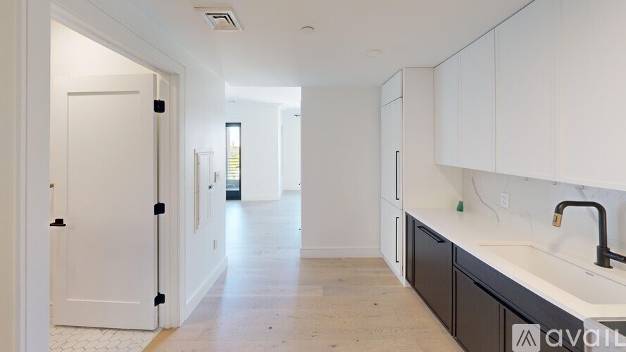 A kitchen with white cabinets and a black faucet.