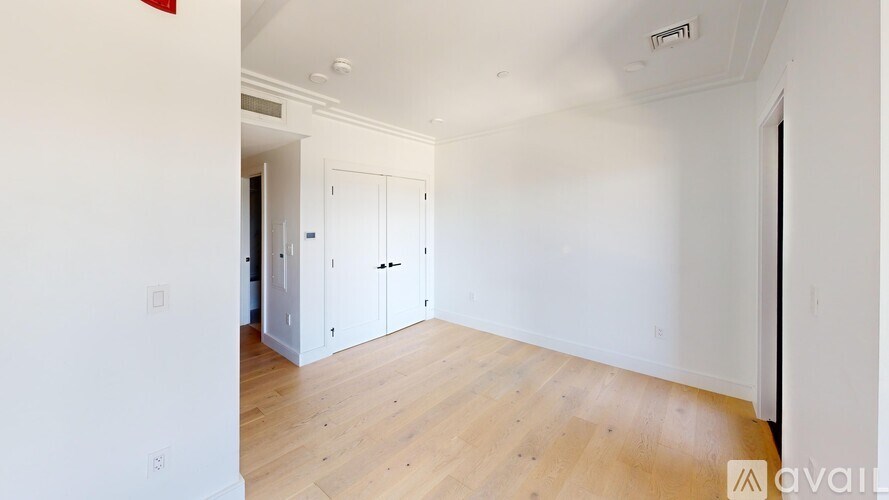 A room with white walls and wooden flooring, with a white cabinet in the middle.