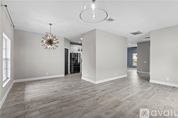 A spacious room with wooden flooring and a chandelier hanging from the ceiling.