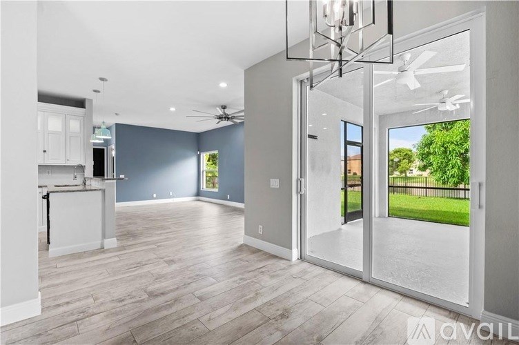 A spacious room with a kitchen area and a view of the backyard through the sliding glass doors.