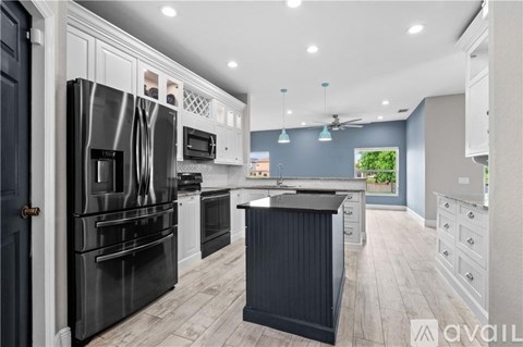 A modern kitchen with a black refrigerator and wooden floors.