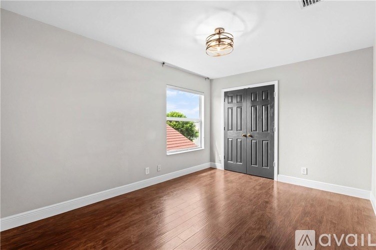 A room with a wooden floor and a grey door.