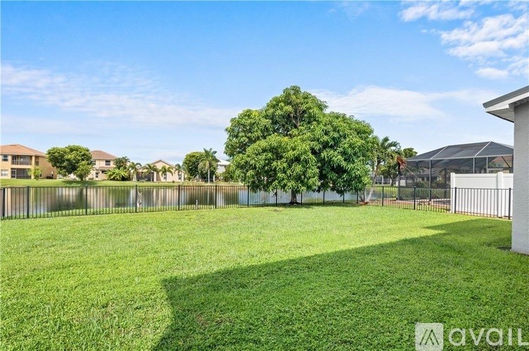 A grassy field with a fence and trees in the background.