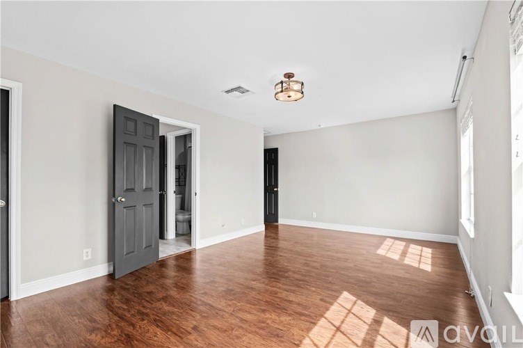 A room with a wooden floor and a grey door.