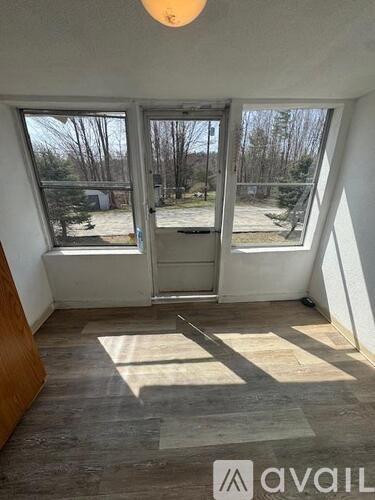 A room with a large window and a view of trees and a driveway.