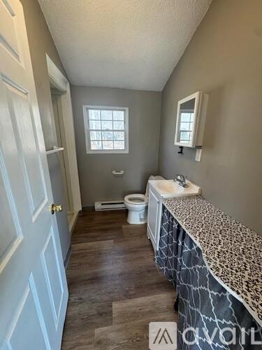 A bathroom with a toilet, sink, and window.