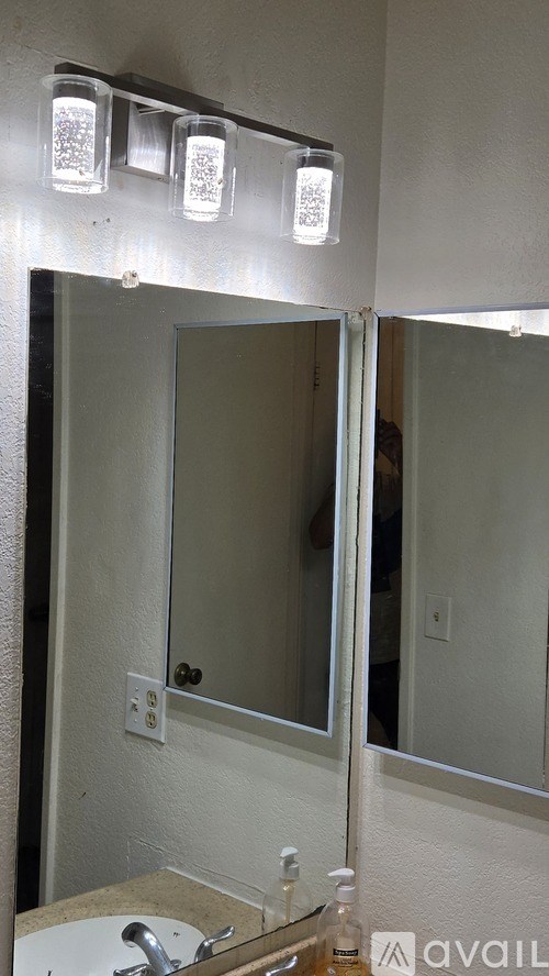A bathroom with a sink, mirror, and lights.