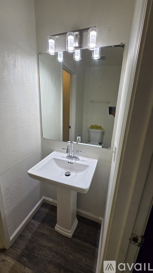 A bathroom with a white sink and a mirror with lights above it.