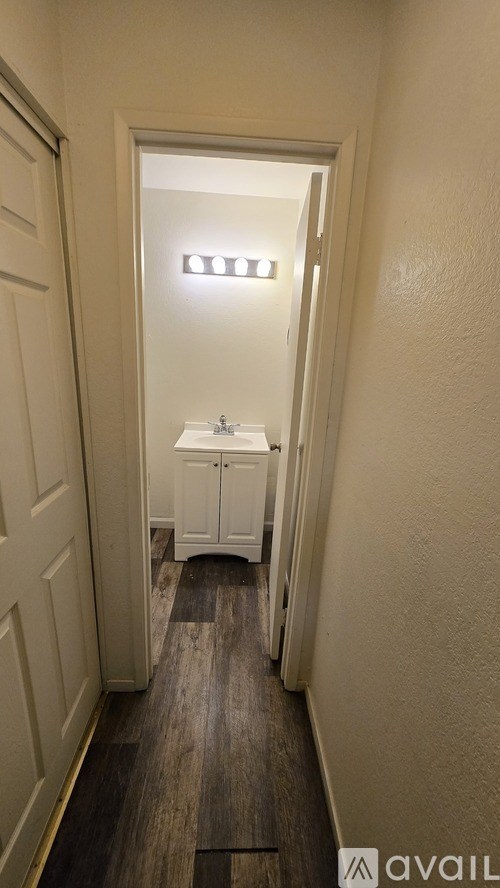 A hallway with a white cabinet and a door at the end.
