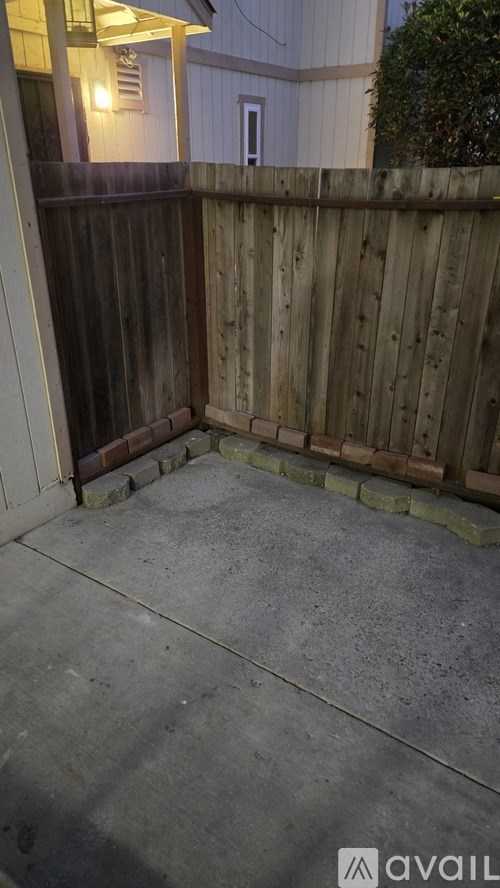 A patio with a wooden fence and concrete floor.