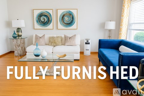 A living room with a white couch and a blue chair.