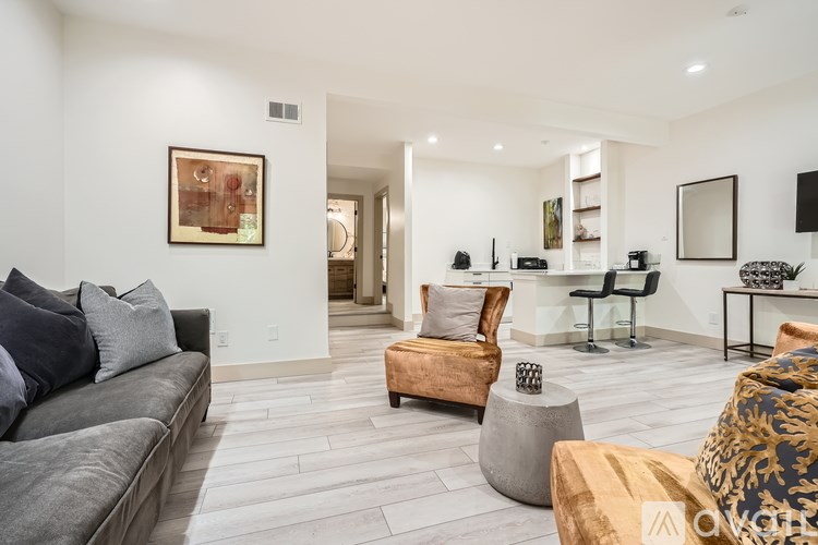 A living room with a grey couch, a brown chair, and a grey ottoman.