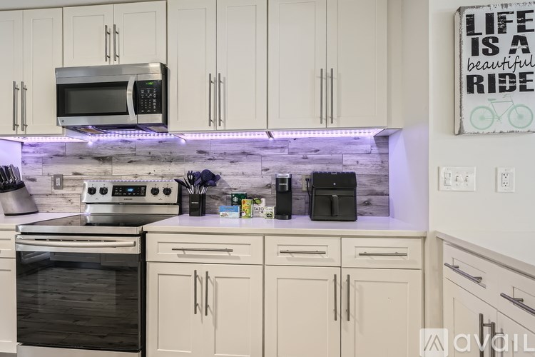 A kitchen with white cabinets and a quote on the wall.