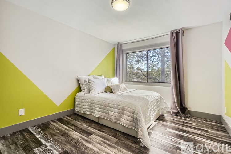 A bedroom with a white bed and a window with curtains.