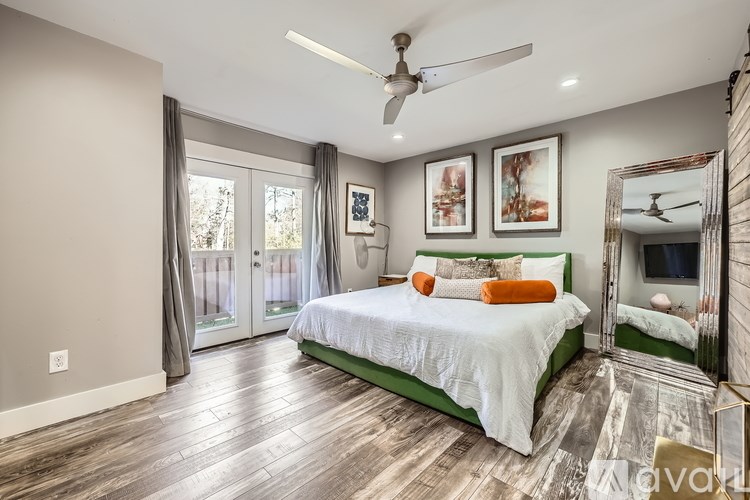 A bedroom with a bed, a ceiling fan, and a mirror.