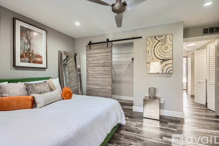 A bedroom with a bed, a mirror, and a ceiling fan.