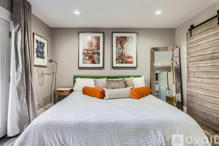A bedroom with a large bed and two framed pictures on the wall.