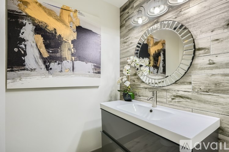 A bathroom with a white sink and a large painting above it.