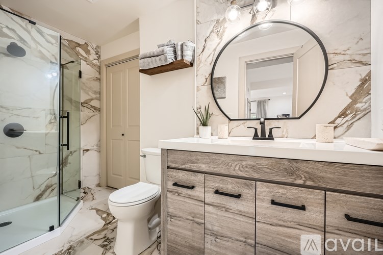 A bathroom with a marble patterned floor and a glass shower stall.