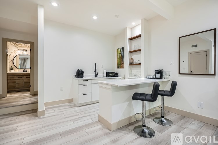 A modern kitchen with white cabinets and a bar area.