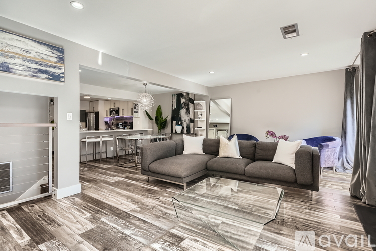 A modern living room with a grey sofa and a wooden floor.