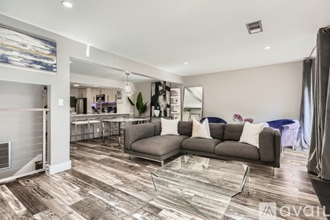 A modern living room with a grey sofa and a wooden floor.
