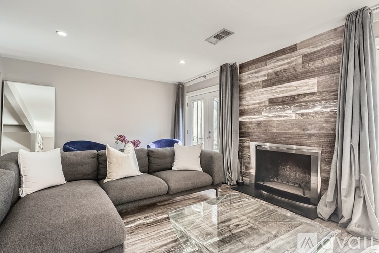 A modern living room with a grey sofa and a fireplace.