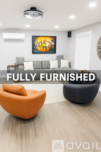 A modern living room with a large orange chair and a black chair with a white cushion.