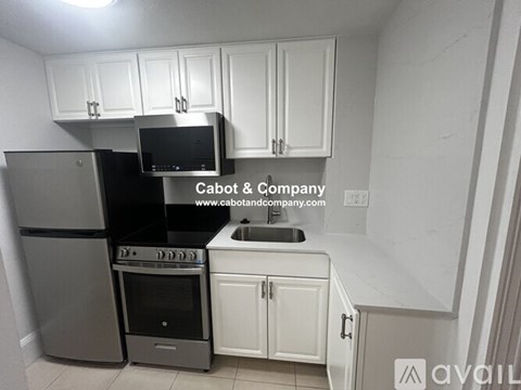 A kitchen with white cabinets and a black microwave above the stove.