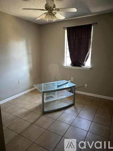 A room with a glass coffee table and a ceiling fan.
