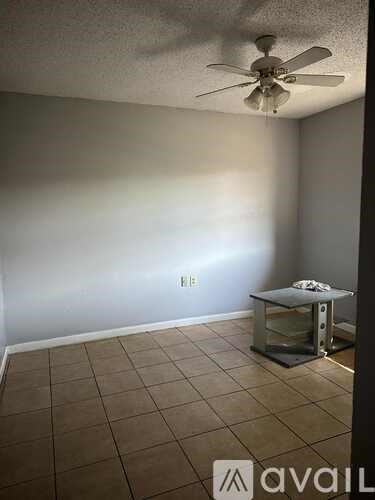 A room with a ceiling fan and a glass table.