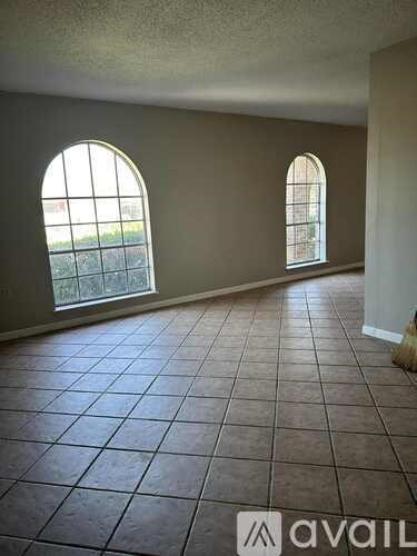 A room with tiled flooring and two arched windows.
