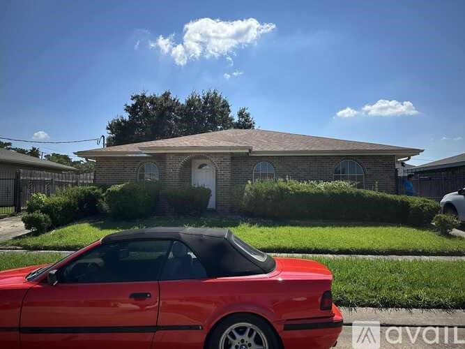 A red convertible car is parked in front of a house.