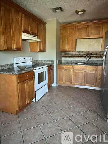 A kitchen with wooden cabinets and a white stove top oven.