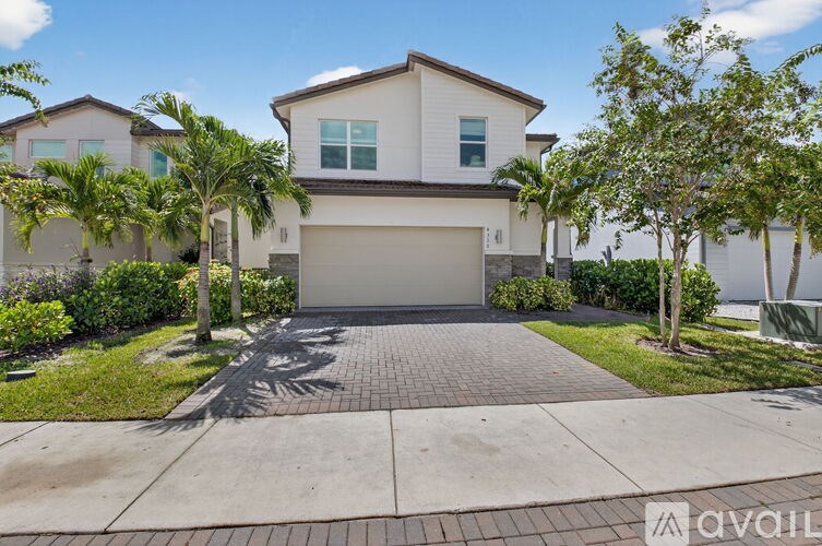 A house with a driveway and palm trees in front.